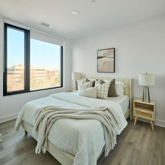 A bedroom with a large bed and a window overlooking a cityscape.