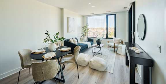A dining room with a table set for two and a couch with a pillow.