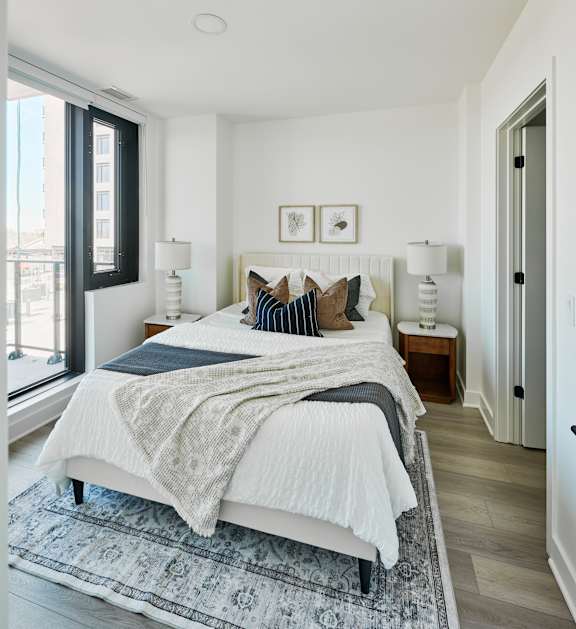 A bedroom with a large bed and a window overlooking a cityscape.