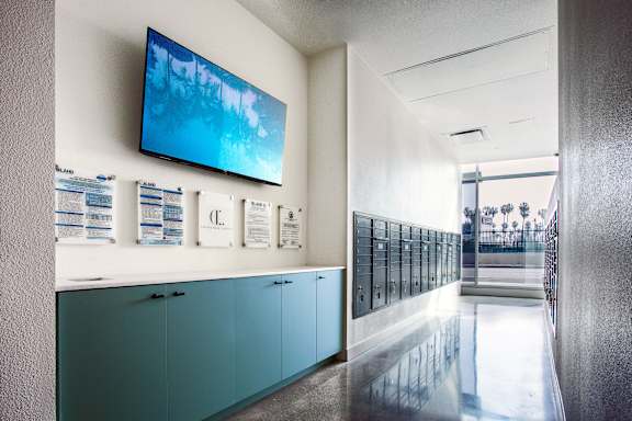A long hallway with a TV mounted on the wall and a row of lockers on the right side.