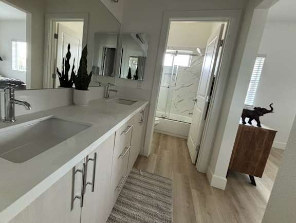 A bathroom with a sink, mirror, and a rug on the floor.