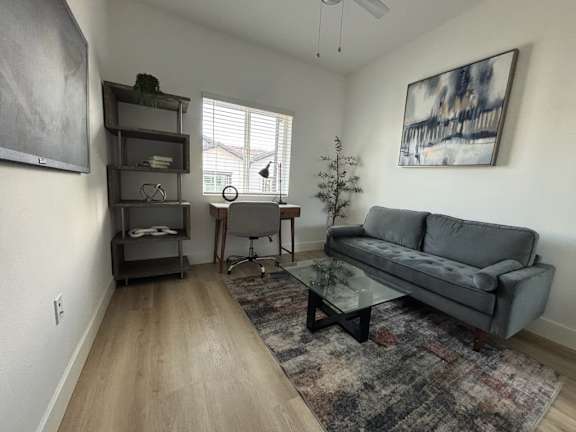 A living room with a grey couch, a glass coffee table, and a TV on a stand.