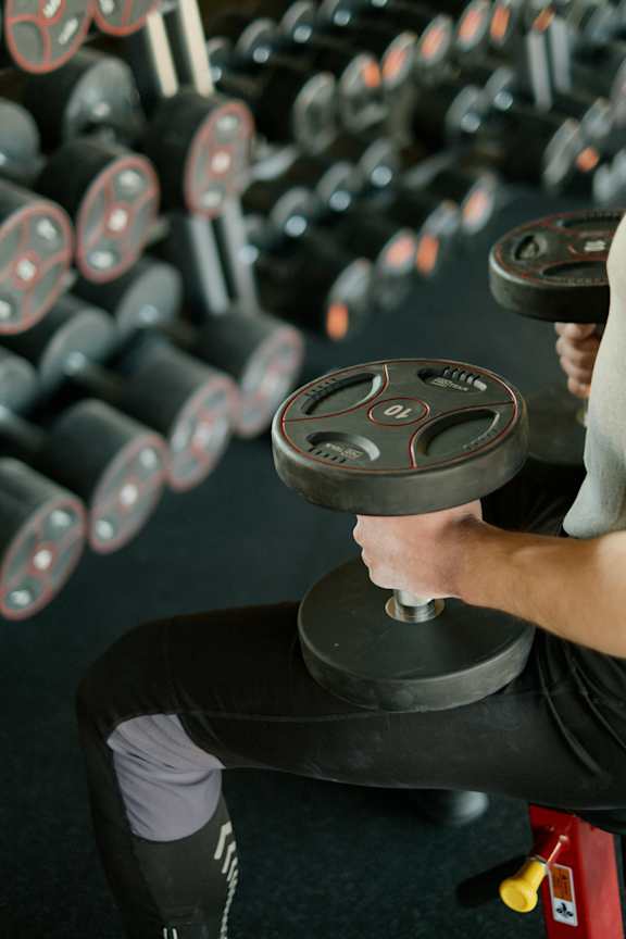 A man lifting a dumbbell in a gym.