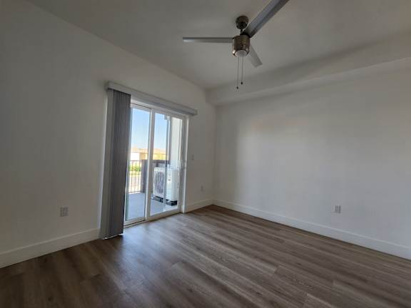 A room with a ceiling fan and sliding glass doors.