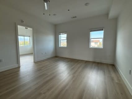 Empty room with wooden floors and two windows.