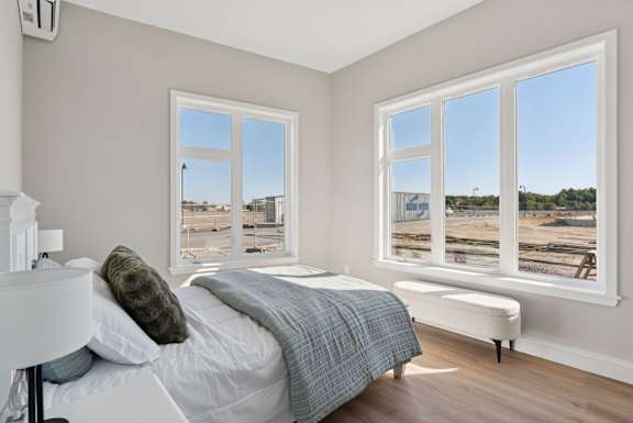 A bedroom with a large bed and a window overlooking a construction site.