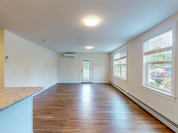 Bright living room with hardwood flooring and natural light at Autumn Woods Apartments, Westbrook, ME