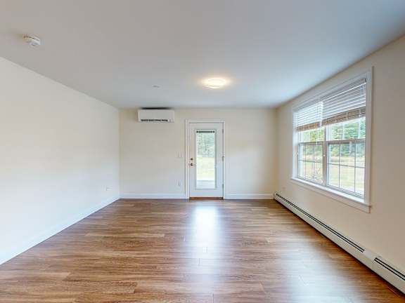 Empty living space with hardwood flooring and door at Autumn Woods Apartments, Westbrook, 04092