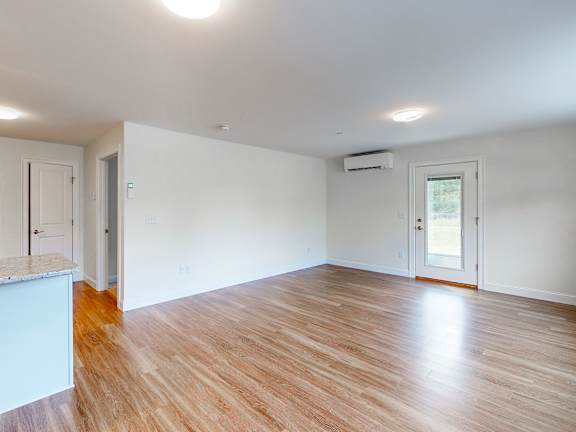 Empty living room with hardwood style flooring at Autumn Woods Apartments, Westbrook, Maine