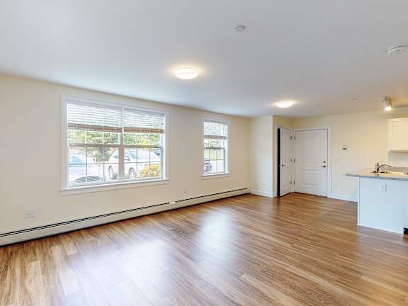Open living space with hardwood flooring and natural light at Autumn Woods Apartments, Maine