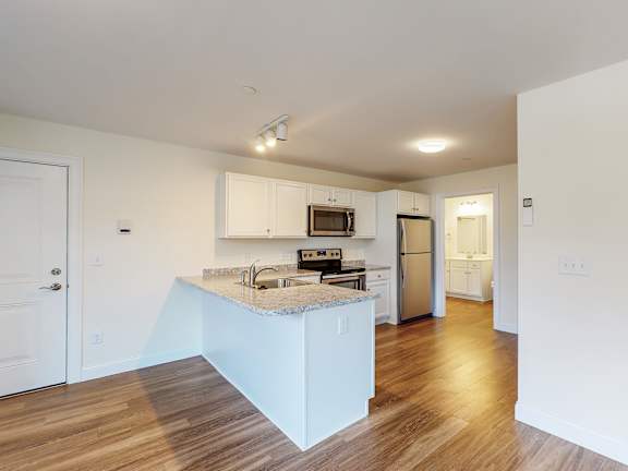 Open kitchen with peninsula island and granite counters at Autumn Woods Apartments, Maine, 04092