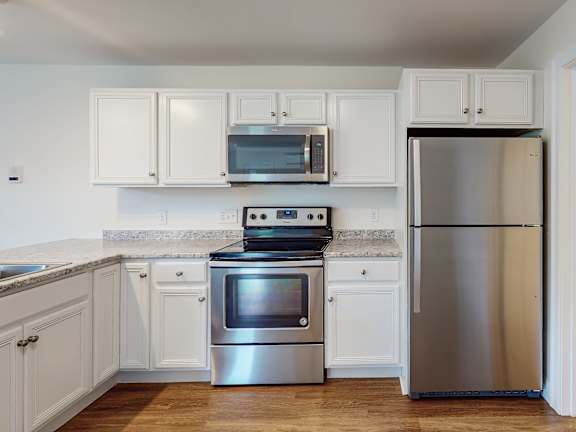 Stainless steel refrigerator and range with white cabinets at Autumn Woods Apartments, Westbrook, 04092