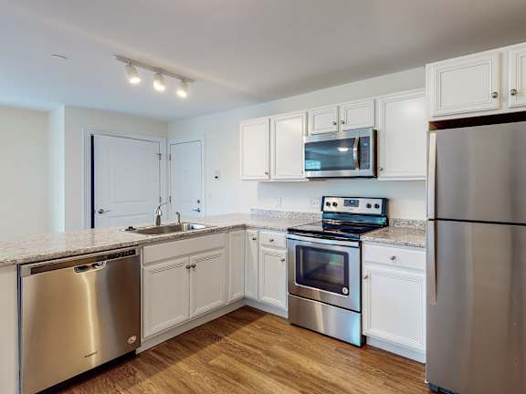 Modern kitchen with stainless refrigerator and range at Autumn Woods Apartments, Westbrook, Maine