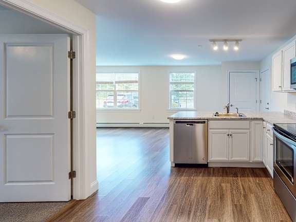 Modern kitchen with white cabinets and wood flooring at Autumn Woods Apartments, Maine