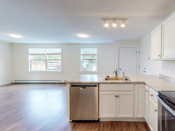 Open concept kitchen with peninsula and wood floors at Autumn Woods Apartments, Maine, 04092