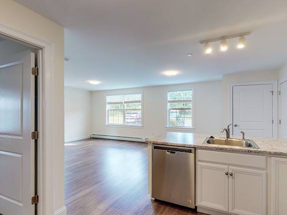 Open kitchen with island and hardwood floors at Autumn Woods Apartments, Westbrook, ME 04092
