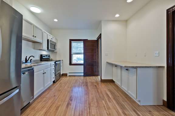 A kitchen with wooden floors and white cabinets.