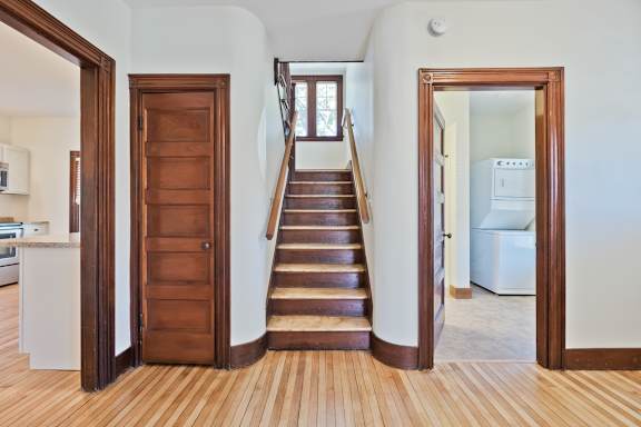 A wooden door is on the left and a white fridge is on the right.