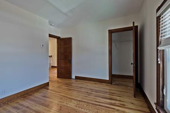 A room with wooden floors and a doorway leading to another room.