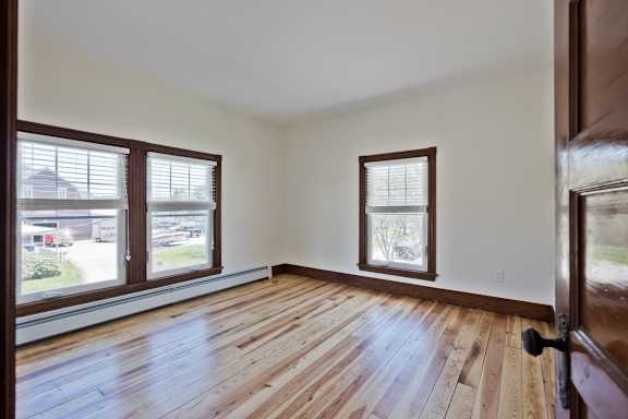 A room with wooden floors and two windows.