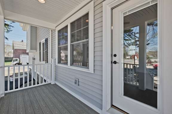 A white door is open to a deck with a railing.