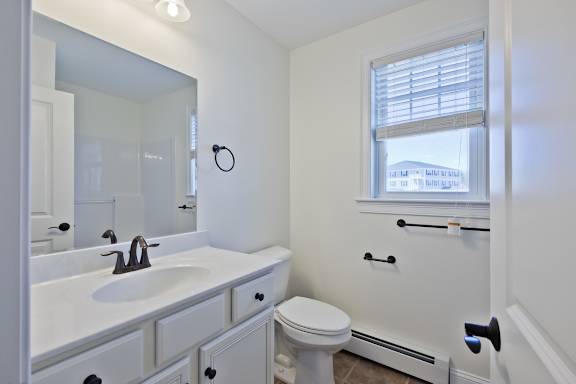 A white bathroom with a toilet, sink, and mirror.