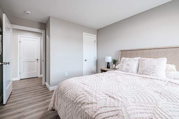 Master bedroom with upholstered headboard and soft lighting at Windham Village Apartments, Windham, Maine