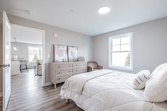 Bright bedroom with large window and wood flooring at Windham Village Apartments, Maine