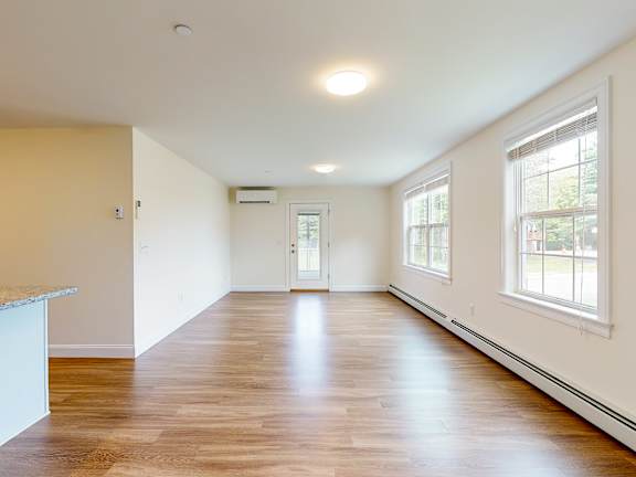 Sunlit living area with hardwood floors and two windows at Autumn Woods Apartments, Maine, 04092
