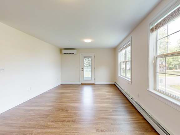 Spacious living room with large windows and door at Autumn Woods Apartments, Westbrook, ME 04092