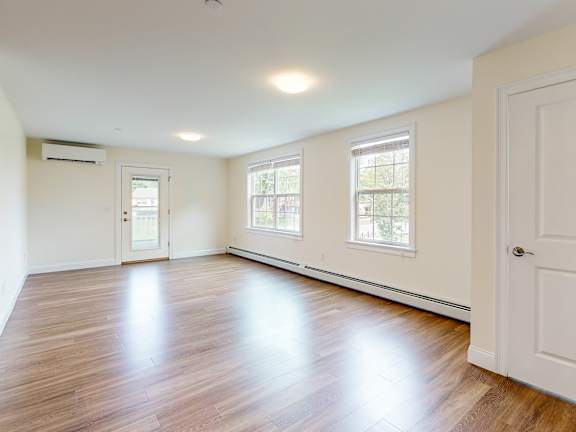 Spacious empty living room with two windows at Autumn Woods Apartments, Westbrook, ME