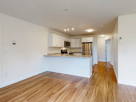 Open kitchen with breakfast bar and hardwood flooring at Autumn Woods Apartments, Maine