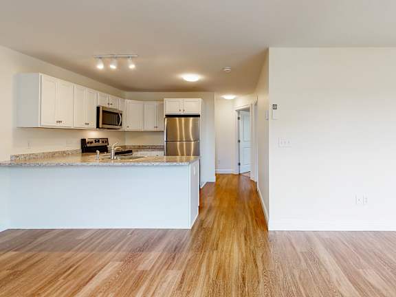 Open kitchen with peninsula and stainless appliances at Autumn Woods Apartments, Maine, 04092