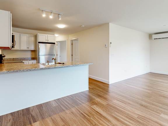 Open kitchen and living area with granite peninsula at Autumn Woods Apartments, Westbrook, ME 04092