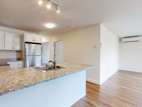 Open kitchen with granite island and stainless appliances at Autumn Woods Apartments, Westbrook, ME