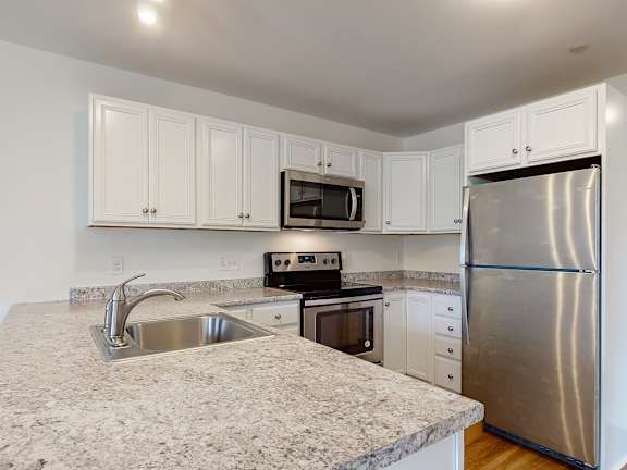 White cabinetry kitchen with granite counters and sink at Autumn Woods Apartments, Westbrook, 04092