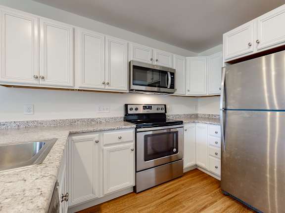 White cabinetry kitchen with stainless steel appliances at Autumn Woods Apartments, Westbrook, Maine