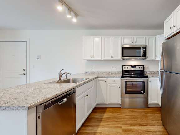 White cabinetry kitchen with granite counters and island at Autumn Woods Apartments, Westbrook