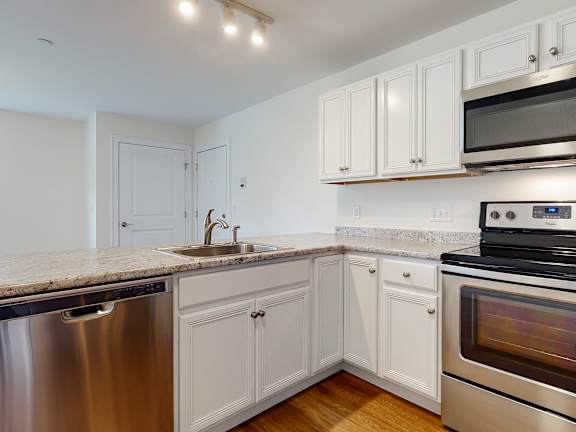 Corner kitchen with stainless dishwasher and hardwood floors at Autumn Woods Apartments, Maine, 04092