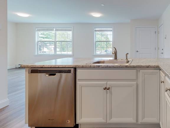 Kitchen island with stainless steel dishwasher and sink at Autumn Woods Apartments, Westbrook, Maine