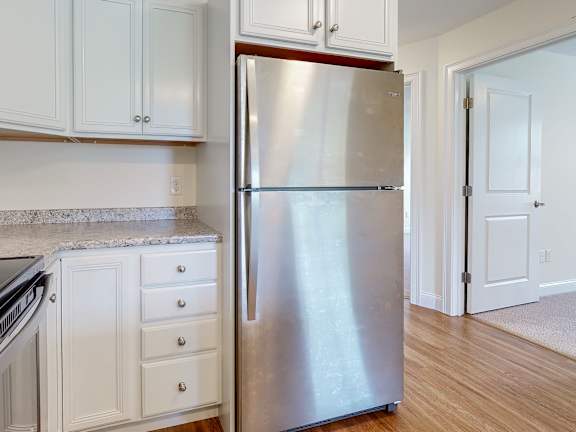 Stainless steel refrigerator in white cabinet kitchen at Autumn Woods Apartments, Westbrook