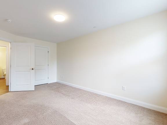 Carpeted bedroom with closet and ceiling light at Autumn Woods Apartments, Westbrook, ME 04092