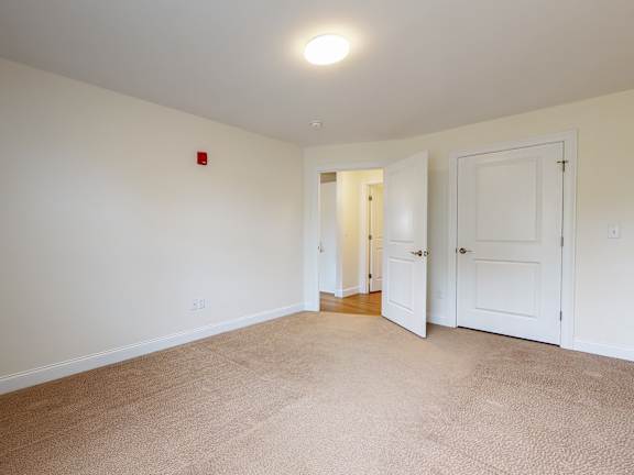 Carpeted bedroom with closet and hallway view at Autumn Woods Apartments, Westbrook, 04092