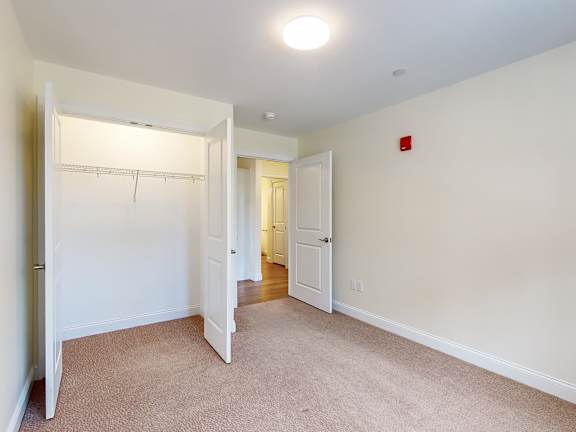 Empty carpeted bedroom with walk-in closet at Autumn Woods Apartments, Westbrook, ME 04092