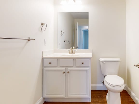 White vanity bathroom with mirror and toilet at Autumn Woods Apartments, Maine