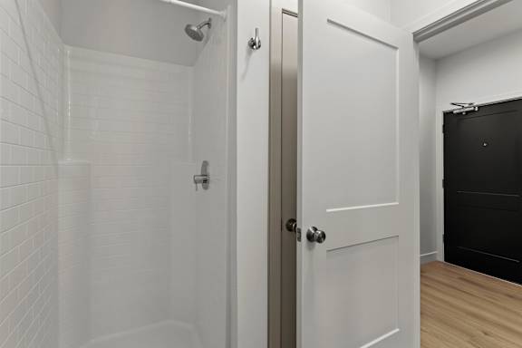a white bathroom with a shower and a white door