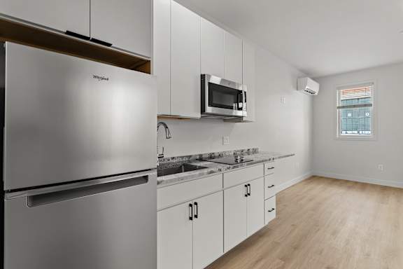 an empty kitchen with white cabinets and a stainless steel refrigerator