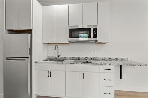 a kitchen with white cabinets and a sink and a microwave