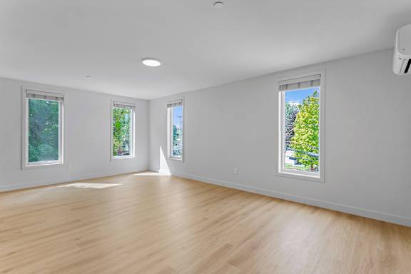 an empty living room with white walls and wood floors