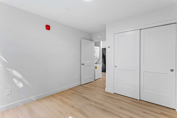 a bedroom with white walls and wooden floors and white closets